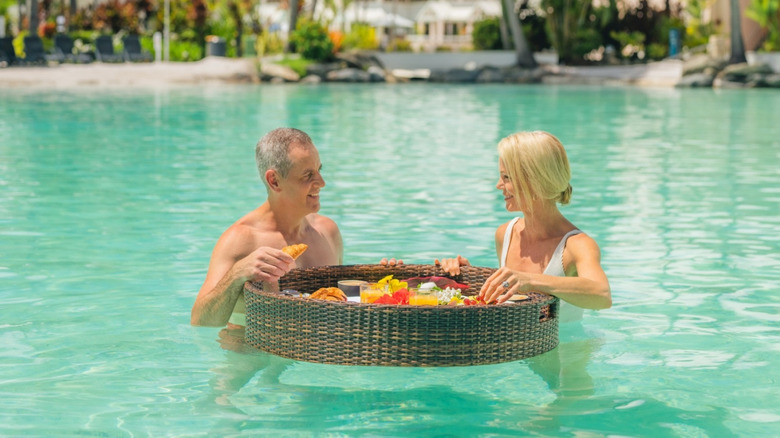 A couple enjoying a floating breakfast in a resort pool