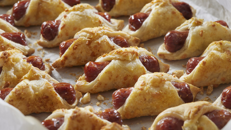 A tray of pigs in a blanket topped with Parmesan cheese