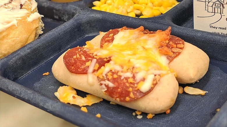 Close-up of two small bread rolls topped with pepperoni and melted cheese on a school lunch tray