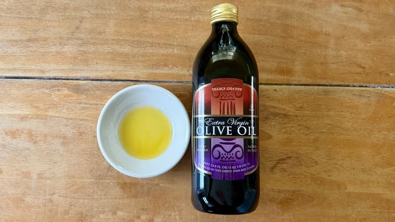 a bottle and white sauce dish of Trader Joe's Extra Virgin Olive Oil, Liter on a wooden table