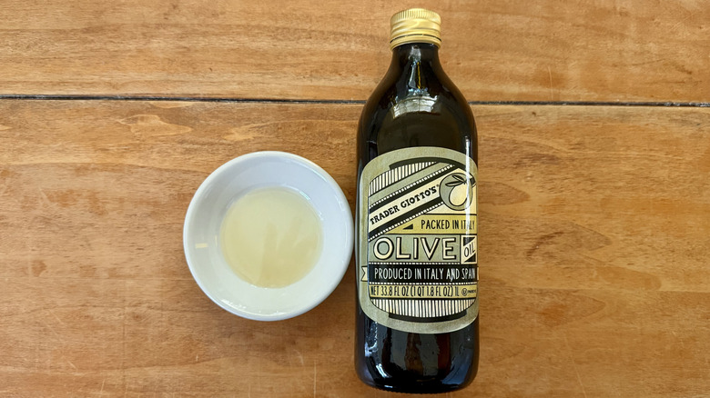 a bottle and white sauce dish of Trader Joe's Imported Olive Oil on a wooden table