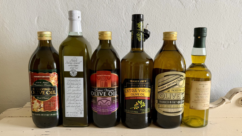 a selection of six Trader Joe's olive oils lined up on white wooden table