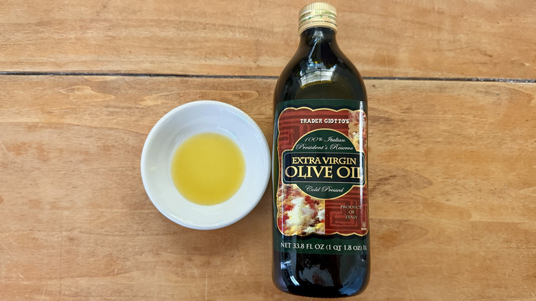 a bottle and white sauce dish of Trader Joe's Italian President's Reserve Extra Virgin Olive on a wooden table