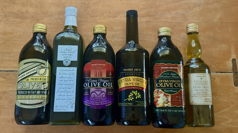 six Trader Joe's olive oils lined up in a row lying down on a wooden table