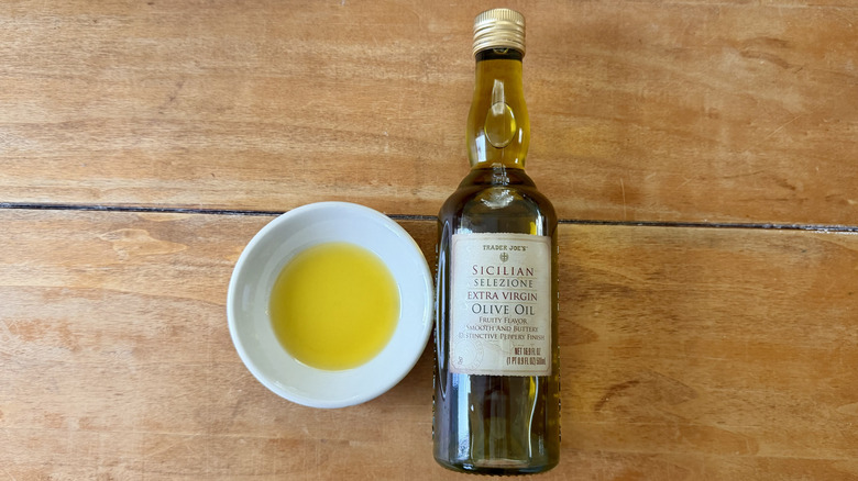 a bottle and white sauce dish of Trader Joe's Sicilian Selezione Extra Virgin Olive Oil on a wooden table