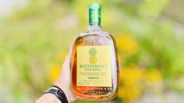 Hand holding bottle of Buchanan's Pineapple Scotch Whisky