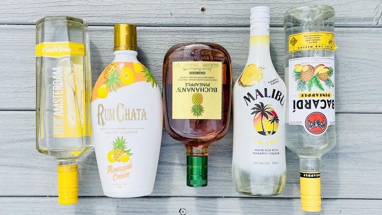 Various bottles of pineapple liquor lying on grey wooden deck