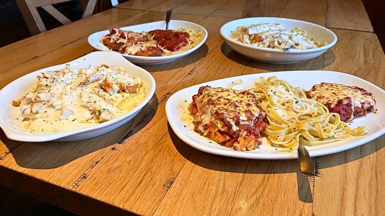 A table with four different Olive Garden entrees
