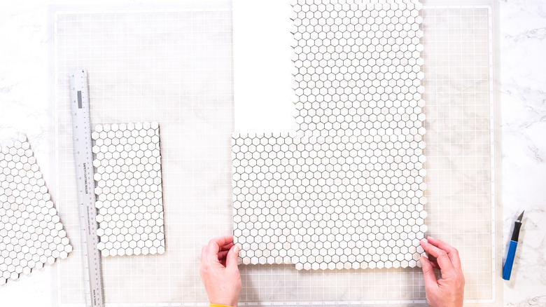 hands holding pieces of peel and stick tile