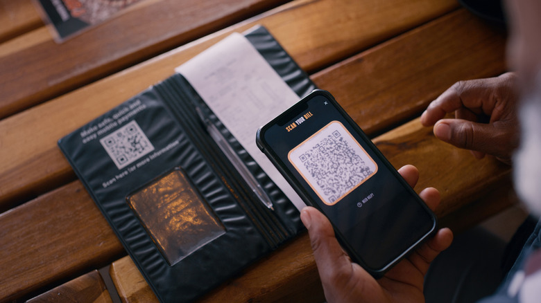 A person paying restaurant bill using QR code and smartphone
