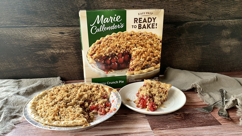 Marie Callender's cherry crunch pie in the pan with a slice on a plate in front of the box