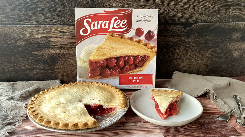 Sara Lee cherry pie in the pan with a slice on a plate in front of the box