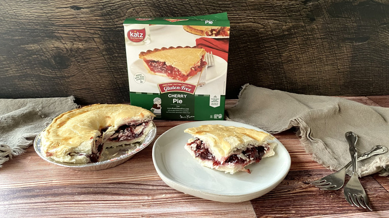 Katz gluten free cherry pie in the pan with a slice on a plate next to the box