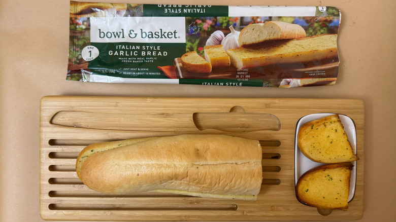 Loaf of Bowl & Basket Italian Style Garlic Bread on wooden board beside product packaging