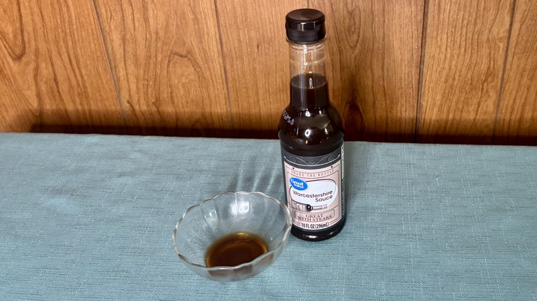 A small glass dish with Worcestershire sauce covering the bottom - a bottle of Great Value Worcestershire Sauce stands behind the dish