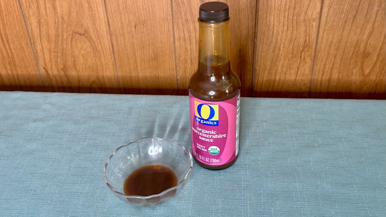 A small glass dish with Worcestershire sauce covering the bottom - a bottle of O Organics Organic Worcestershire Sauce stands behind the dish