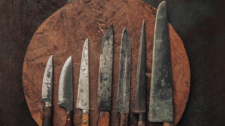 various vintage carbon steel knives on a circular cutting board