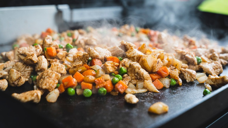close-up shot of chicken and veggie stir-fry on a griddle