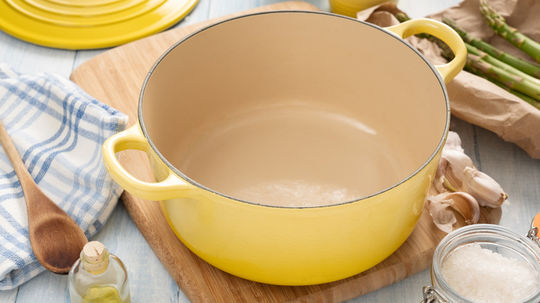 A yellow dutch oven on a wooden cutting board