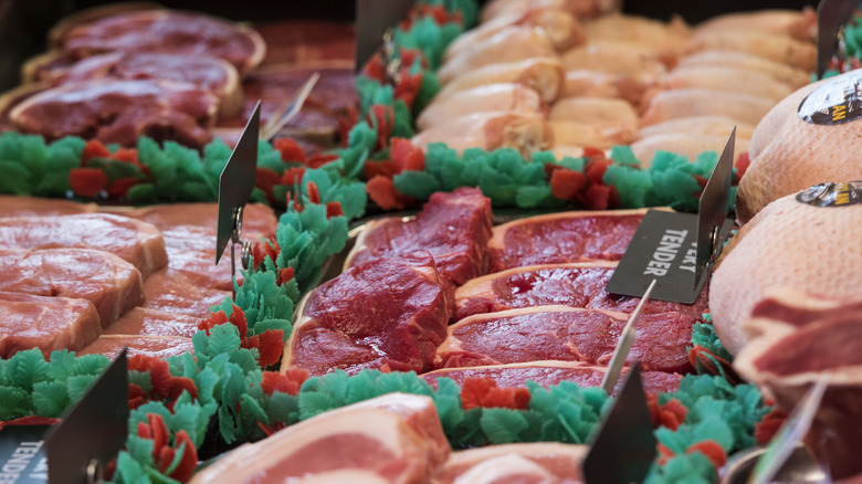 Six sections of a butcher's shop display with meat for sale and labeling placards