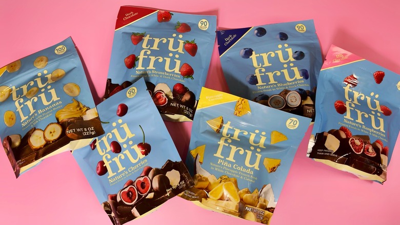6 different flavors of Trü Frü bags laid out on a pink background