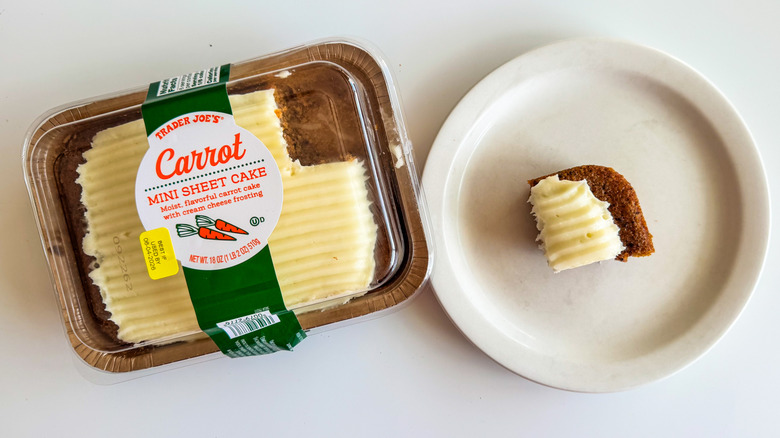 Trader Joe's carrot mini sheet cake in a plastic container with a small piece on a white plate against a white surface