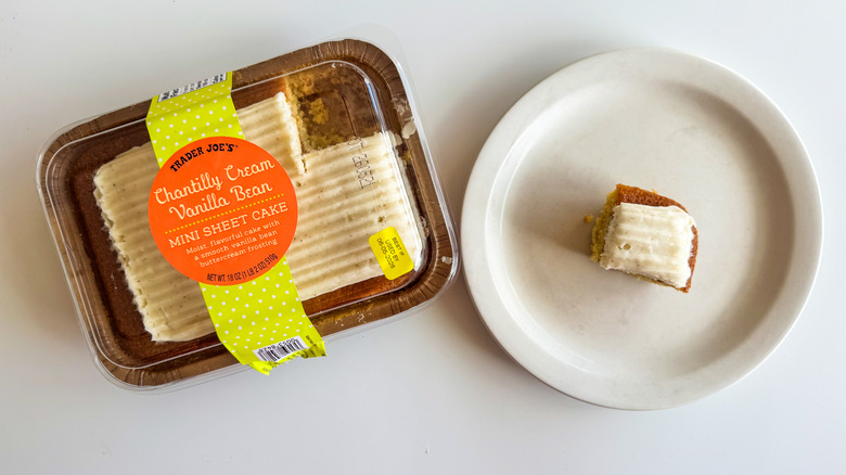 Vanilla sheet cake in its packaging with a small piece on a plate on a white surface