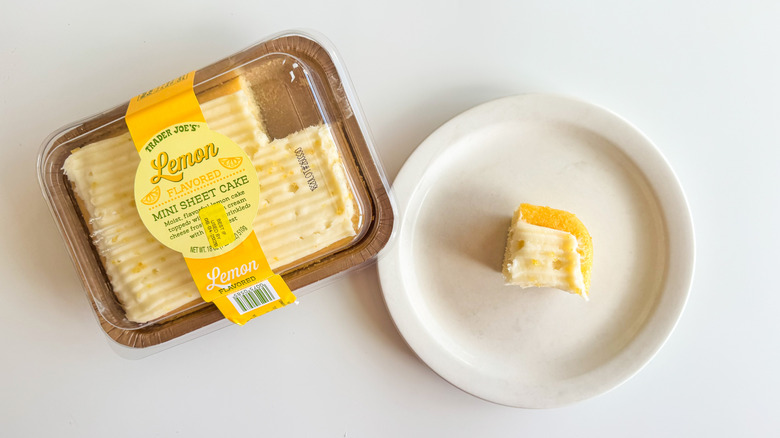 Lemon mini sheet cake on a plate next to a box of lemon sheet cake on a white surface