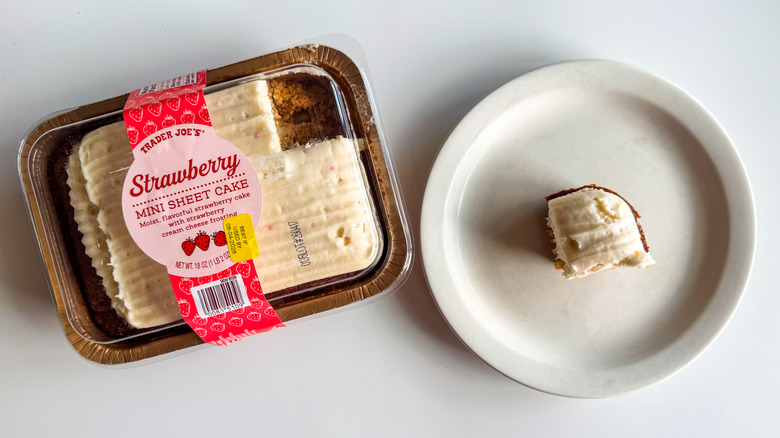 Trader Joe's strawberry mini sheet cake in a plastic container with a small piece on a plate next to it on a white surface