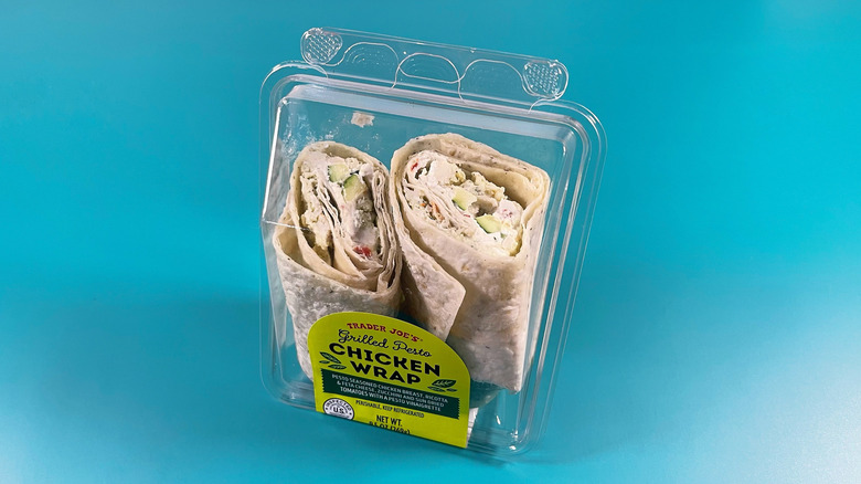 Trader Joe's Grilled Pesto Chicken Wrap in a plastic container on a teal background