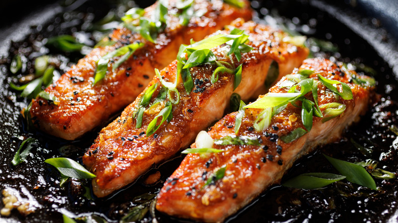 A plate of teriyaki salmon filets sprinkled with chopped scallions
