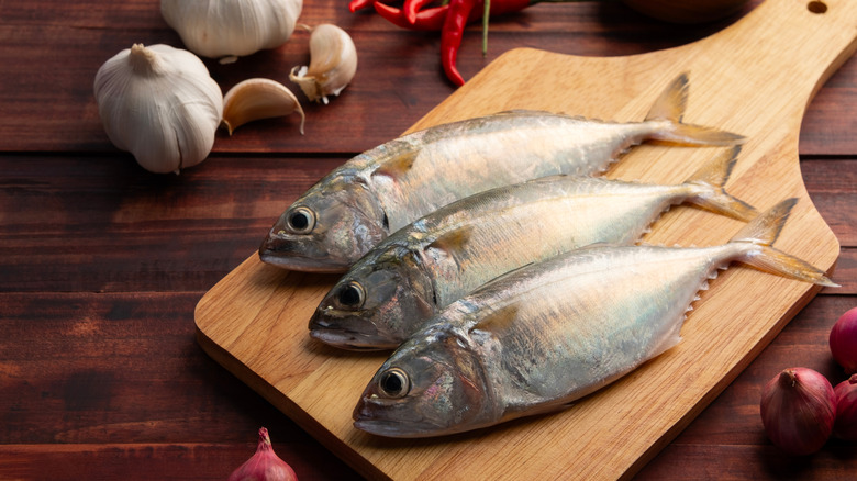 Three whole mackerel on a cutting board