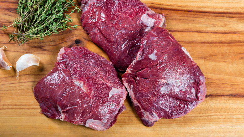 Raw beef cheeks on a board