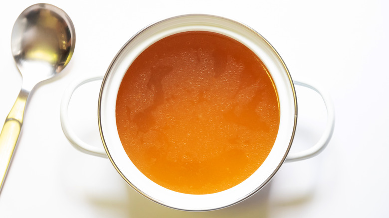 a pot of clear broth with a serving spoon
