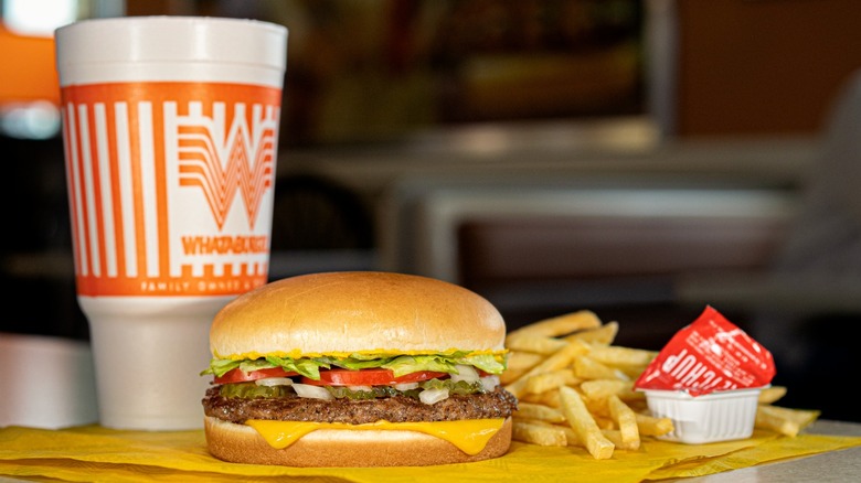 a Whatameal from Whataburger with a drink, burger, fries and Whataburger ketchup set out on table