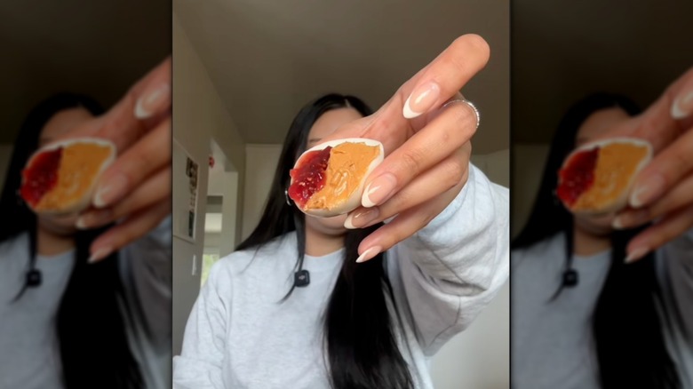 woman holding peanut butter and jelly egg in front of her face