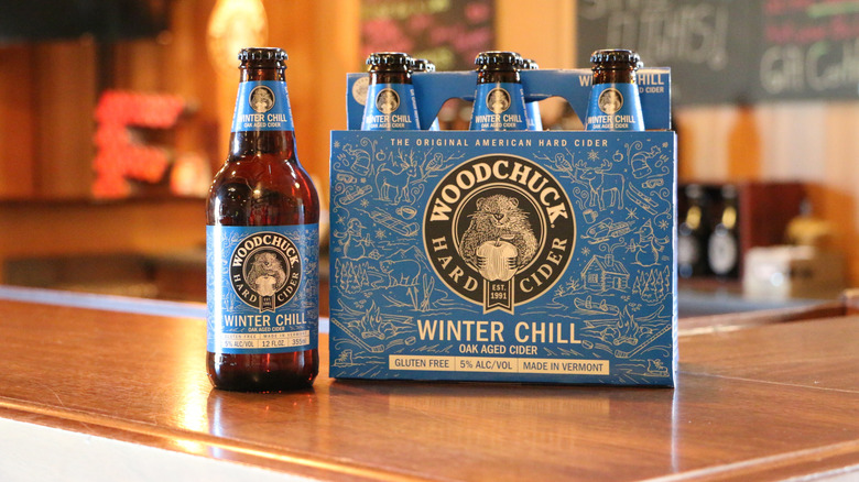 A six pack of Woodchuck Hard Cider's Winter Chill variety, with one bottle out next to the six pack
