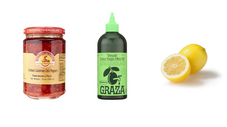 A bottle of Calabrian chili paste, olive oil, and sliced lemon on a white isolated background