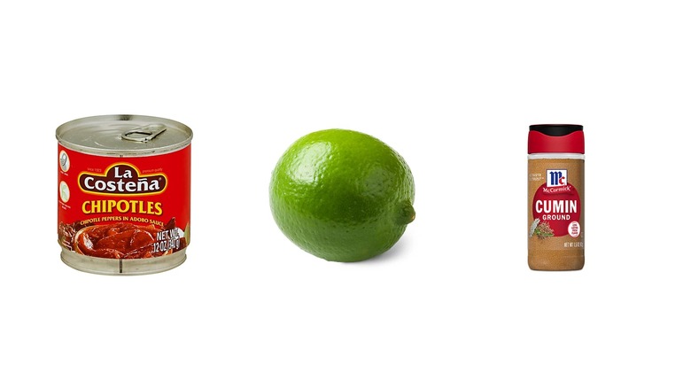 A can of chipotles in adobo sauce, a lime, and a bottle of ground cumin on a white isolated background