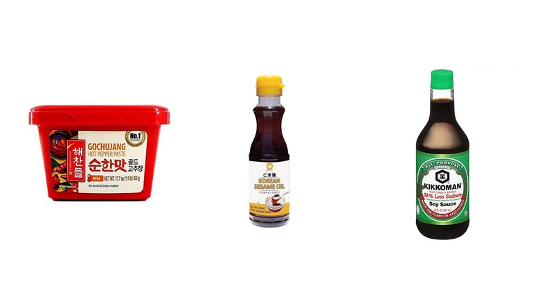 A container of gochujang alongside a bottle of sesame oil and soy sauce