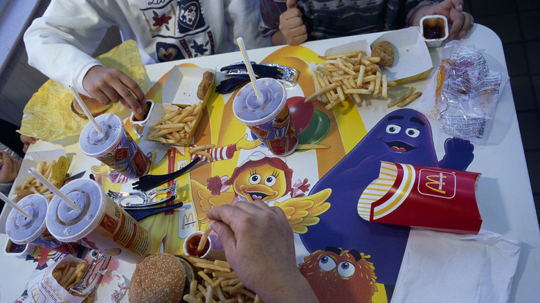 Family eating McDonald's meal with mascots depicted on the dining table peaking through