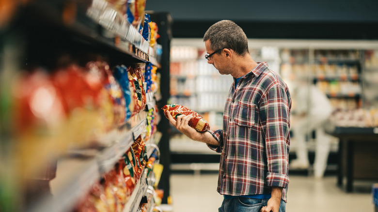 Man looking at a bag and comparison shopping at the supermarket