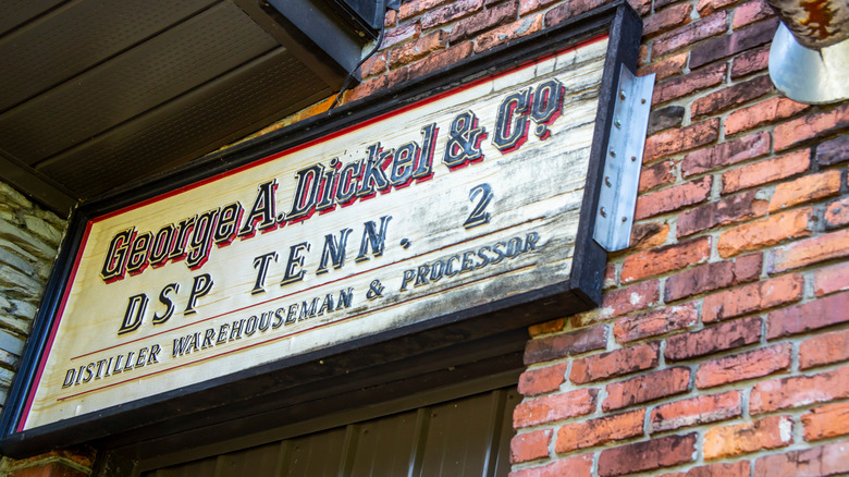 Old wooden sign for George Dickel Distillery on brick building