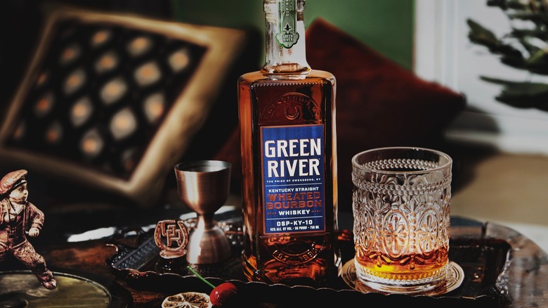 Green River Distillery Wheated Bourbon bottle next to glass on a tray in a formal study-type setting