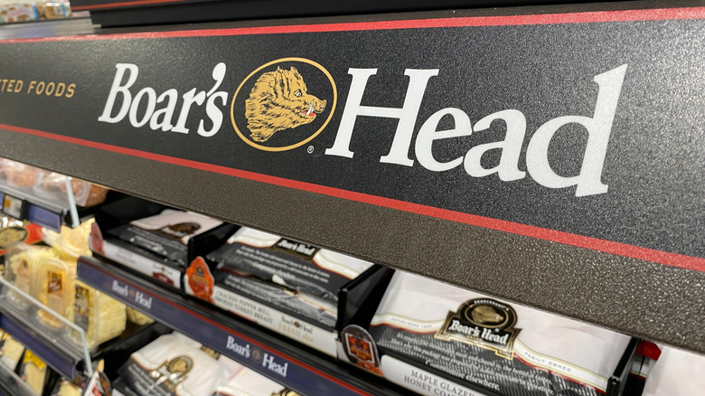 Deli display of Boar's Head brand meats with a gold, red, and black sign above