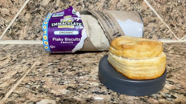 Opened can of Immaculate Baking Company Organic Flaky Biscuits with a cooked one in front