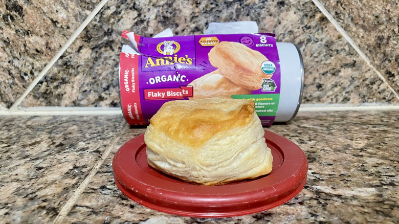 Opened can of Annie's Organic Flaky Biscuits with a cooked one in front