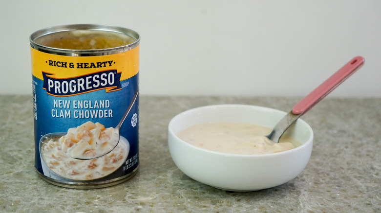Progresso Rich & Hearty New England Clam Chowder next to bowl with chowder and spoon