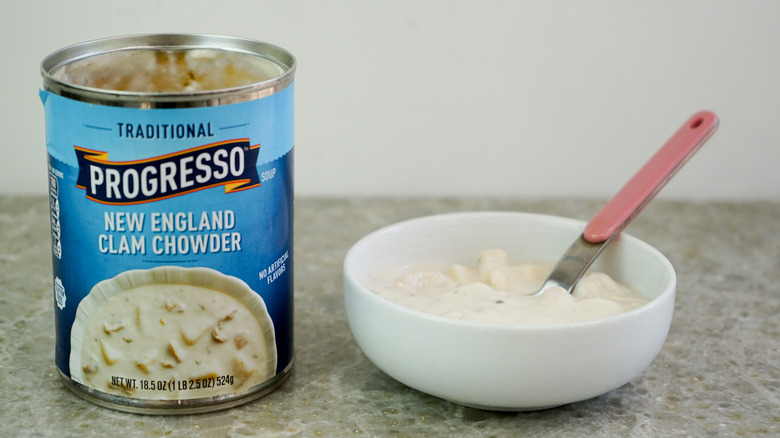 Traditional Progresso New England Clam Chowder next to bowl with chowder and spoon
