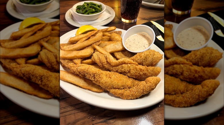 Mirror image of fried catfish and fries from Texas Roadhouse with tartar sauce, a lemon wedge, and a side of green beans